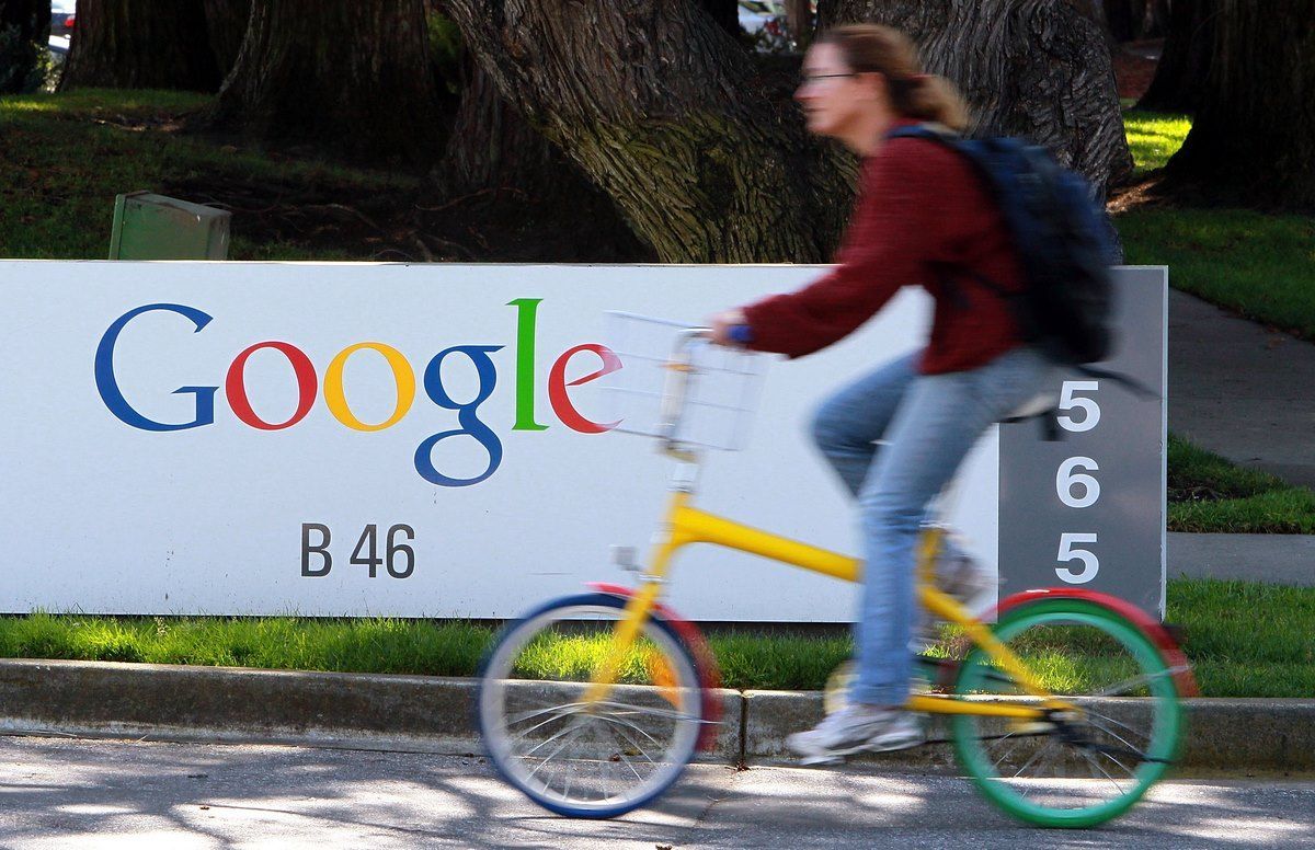 Una donna passa in bicicletta davanti all'insegna di Google