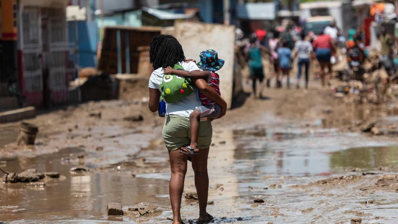 Donna con bambino camminano tra le strade di Haiti